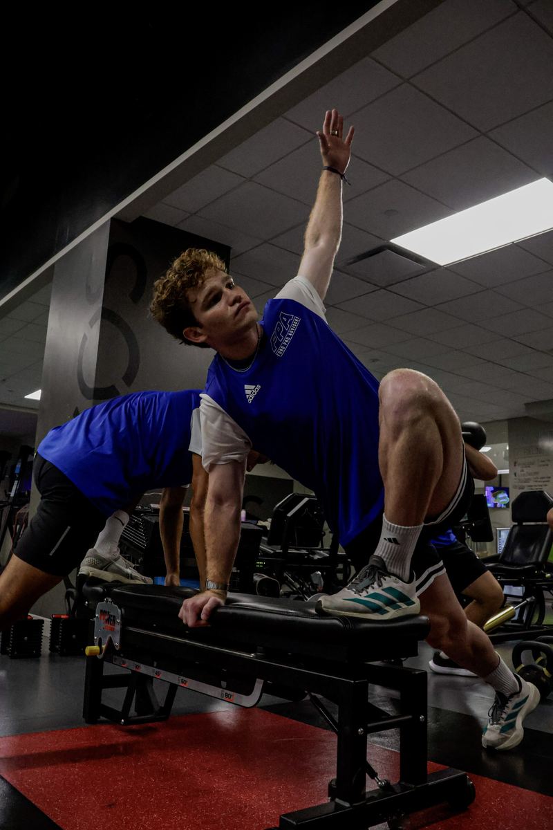 An FPA player driving through a single-leg strength rep in the EXOS weight room.
