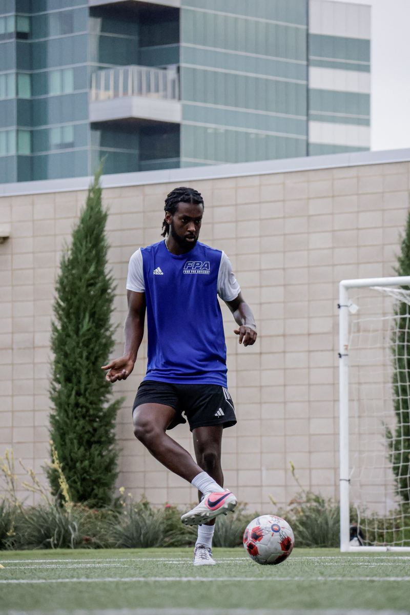 An FPA player striking a ball toward goal during finishing work.